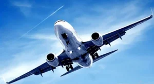 Aereo visto dal basso in volo contro un cielo azzurro con una scia di condensazione, che trasmette dinamismo e potenza.