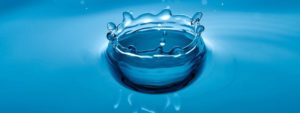 Spruzzo d'acqua che forma una corona su sfondo blu uniforme.
