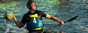 Giocatore di kayak polo con casco e giubbotto numero 4, in azione sull’acqua con palla e pagaia.