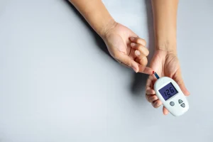 Mani che misurano la glicemia con un glucometro portatile bianco, valore sullo schermo 126 mg/dL