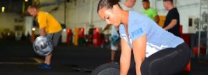 Allenamento in palestra con persone che sollevano pesi e kettlebell, atmosfera intensa e dinamica