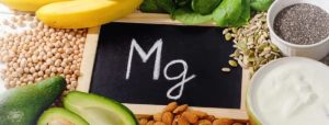 Composizione di alimenti ricchi di magnesio con simbolo Mg su lavagnetta centrale: banane, spinaci, semi, yogurt, mandorle, avocado e ceci