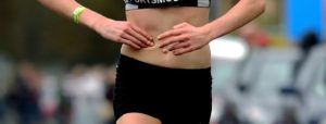 Persona in abbigliamento sportivo con le mani sui fianchi, all’aperto, su sfondo sfocato
