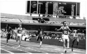 Gruppo di atleti in bianco e nero che corre su una pista d'atletica verso il traguardo.