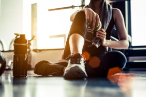 Persona in palestra durante una pausa, con un asciugamano intorno al collo e una mela verde nella mano.
