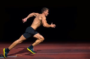 L’immagine mostra un atleta in posizione di sprint, con muscoli evidenziati da uno sfondo scuro. Rappresenta l’ipertrofia funzionale, legata a forza, velocità e prestazione.