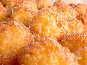 L'immagine rappresenta una visualizzazione scientifica ad alta definizione del tessuto adiposo umano. Le cellule di grasso, globulari e lucenti, appaiono nei toni del giallo-arancio, circondate da una rete filamentosa biancastra. Questa illustrazione enfatizza la struttura cellulare del tessuto adiposo, utile per scopi educativi, medici e nutrizionali, trasmettendo il ruolo chiave del grasso corporeo nel metabolismo e nella salute umana.