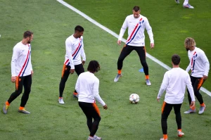 Sei calciatori della nazionale olandese si allenano in cerchio sul campo verde durante una sessione di riscaldamento con il pallone.