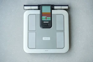 Bilancia digitale con maniglie e display per l’analisi della composizione corporea tramite bioimpedenza, che misura massa grassa, muscolare e grasso viscerale.