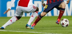 Duello per il pallone tra Lionel Messi del Barcellona e un difensore dell’Ajax durante una partita di UEFA Champions League.