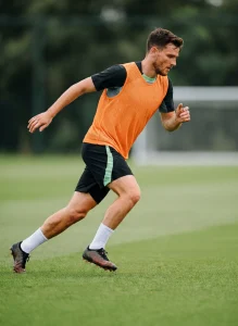 Calciatore durante un esercizio di sprint e agilità in allenamento su campo da calcio in erba