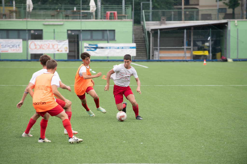 Giovani calciatori durante un esercizio di possesso palla, con un giocatore che conduce il pallone mentre altri lo pressano sul campo.